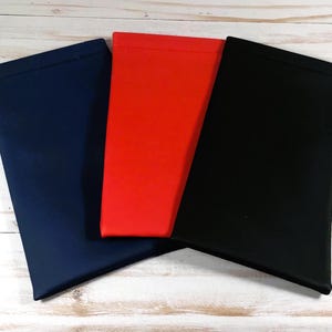 May include: Three fabric pouches in navy blue, red, and black. The pouches are made of a soft, smooth material and have a simple, rectangular shape.