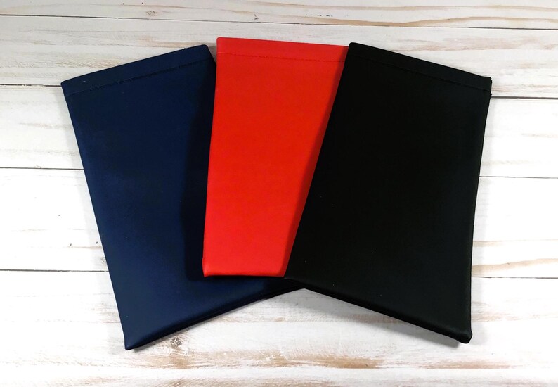 May include: Three fabric pouches in navy blue, red, and black. The pouches are made of a soft, smooth material and have a simple, rectangular shape.
