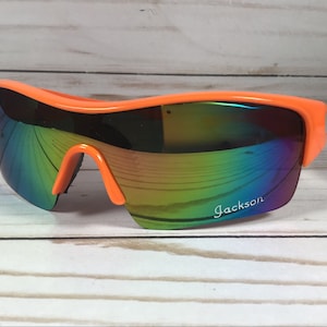 May include: Orange sunglasses with a rainbow iridescent lens and the word "Jackson" printed on the right lens.