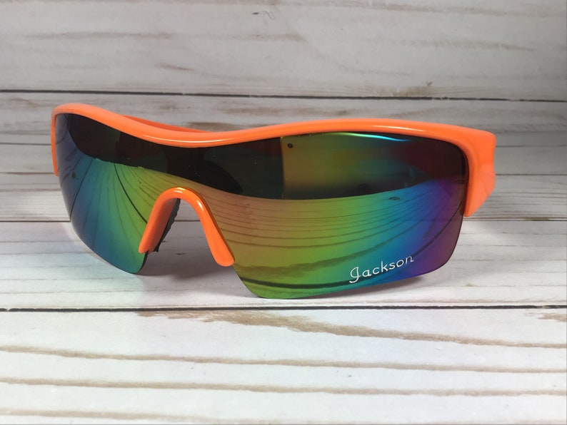 May include: Orange sunglasses with a rainbow iridescent lens and the word "Jackson" printed on the right lens.