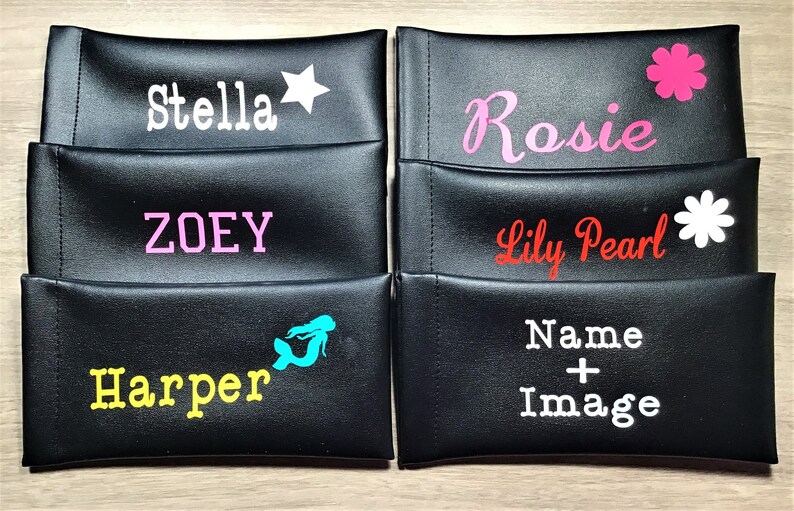 May include: Five black zippered pouches with different names and images printed on them. The names are Stella, Zoey, Rosie, Lily Pearl, and Harper. The images are a star, a flower, a flower, a mermaid, and a plus sign.