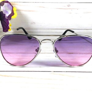 Peut inclure: Lunettes de soleil aviateur argent&eacute;es avec des verres d&eacute;grad&eacute;s passant du rose au violet.