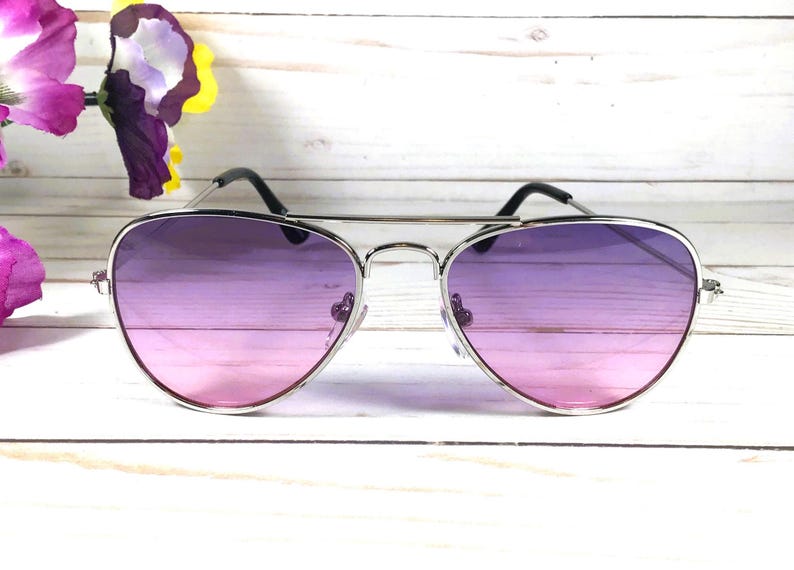 Peut inclure: Lunettes de soleil aviateur argent&eacute;es avec des verres d&eacute;grad&eacute;s passant du rose au violet.