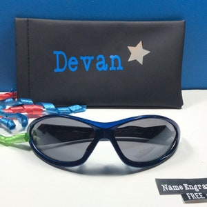 May include: Blue sunglasses with a black case. The case has the name "Devan" and a silver star printed on it. The text "Name Engraved FREE" is printed on a white label.
