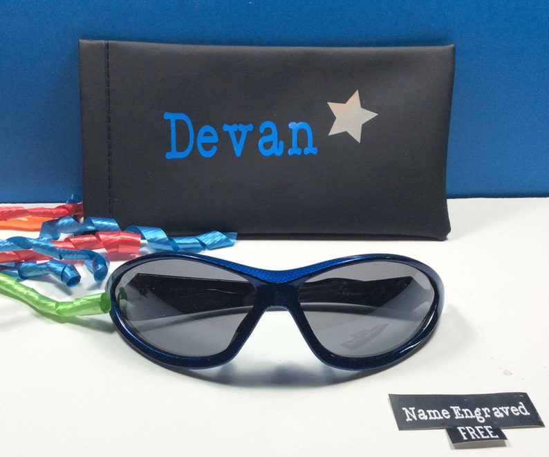 May include: Blue sunglasses with a black case. The case has the name "Devan" and a silver star printed on it. The text "Name Engraved FREE" is printed on a white label.