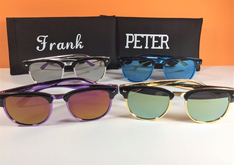 May include: Four pairs of sunglasses with different colored lenses and frames. The sunglasses are arranged in a row on a white surface. The sunglasses are labeled "Frank" and "PETER".
