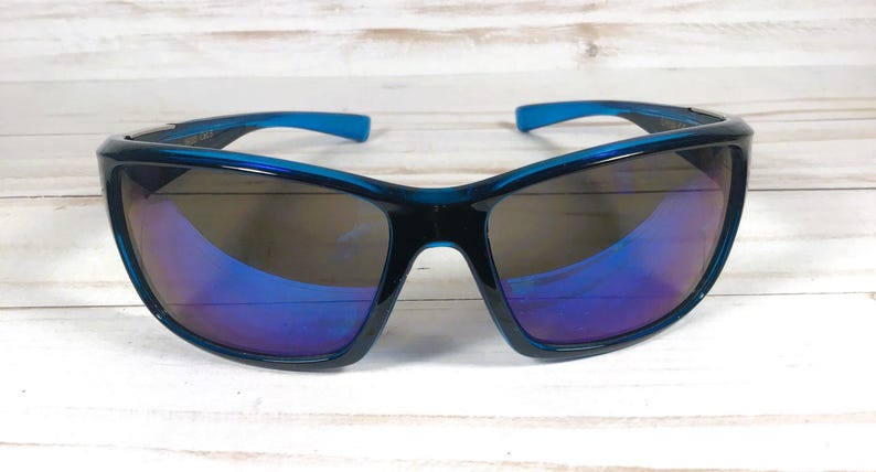May include: Sport sunglasses with a dark teal frame and blue accents on the temples. The lenses have a mirrored finish with shades of blue and purple. The sunglasses are designed for outdoor activities.
