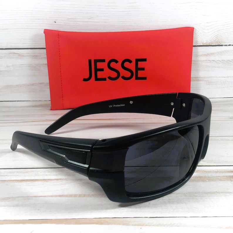 Pu&ograve; includere: Occhiali da sole neri avvolgenti con lenti scure. Un astuccio rosso con il nome "JESSE" in lettere bianche &egrave; dietro gli occhiali da sole. Gli occhiali da sole hanno "UV Protection" stampato sulla montatura.