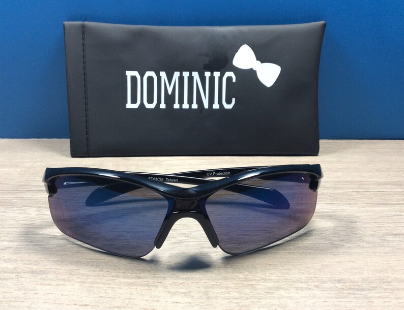May include: Black sunglasses with a dark blue gradient lens and a black case with the word "DOMINIC" printed in white.