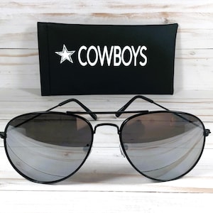May include: Black aviator sunglasses with mirrored lenses and a black case that says "COWBOYS" in white lettering.