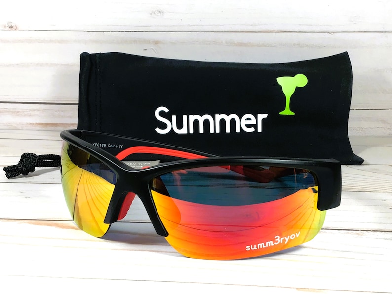 May include: Black sunglasses with orange and yellow reflective lenses featuring the text summ3ryov on the right lens. The sunglasses are accompanied by a black storage pouch with the word Summer and a lime green cocktail glass icon printed on it.