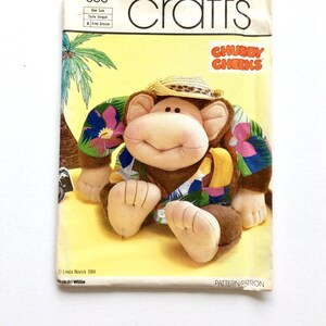 May include: A Simplicity Crafts pattern for a plush monkey toy. The monkey is wearing a tropical shirt and a straw hat. The pattern is called "Chubby Cheeks" and is number 350.