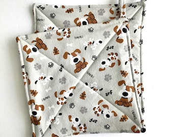 May include: Two square, light gray pot holders with a repeating pattern of brown and white cartoon dogs, paw prints, and bones. The pot holders have a quilted design and a loop for hanging. The words "bark!" and "arf" are also printed on the fabric.