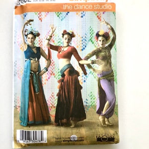 May include: Simplicity sewing pattern for "the dance studio" featuring three dancers in colorful belly dance costumes. The pattern number is 3832, with sizes HH 6, 8, 10, and 12. The pattern includes the text "Sign-up for our free newsletter today at simplicity.com."