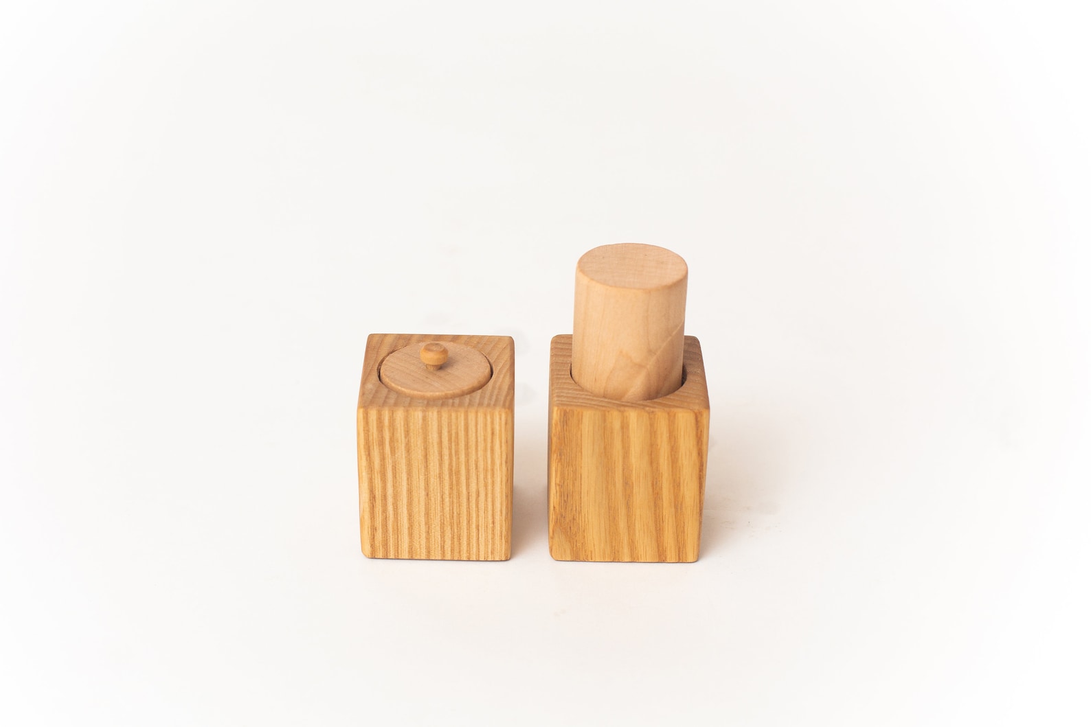 2 Wooden Blocks with cylinders. One cylinder has a knob to grab the other is sticking out of the block to grasp with your palm.