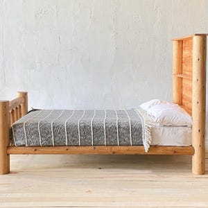 May include: A rustic wooden bed frame with a headboard and footboard. The bed is made of light-colored wood and features a gray and white striped blanket and a white pillow. The bed frame is approximately 75 inches long.