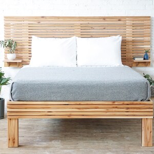 May include: A wooden bed frame with a slatted headboard and footboard. The bed has a gray duvet and two white pillows. There are small shelves on either side of the headboard.