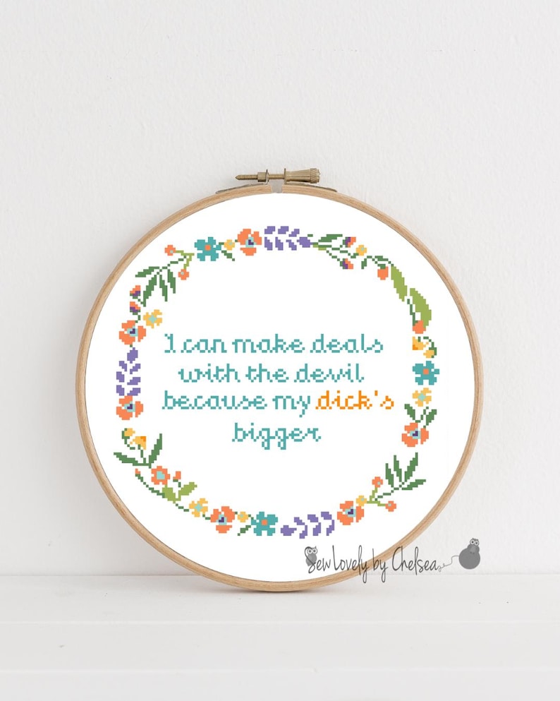 Peut inclure: Un cercle de broderie au point de croix avec le texte "I can make deals with the devil because my dick's bigger" en turquoise. Le texte est entour&eacute; d'une couronne florale aux couleurs vives, notamment orange, bleu, vert et violet.