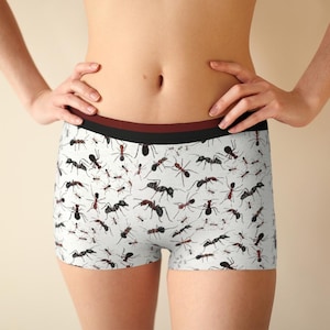 May include: White boxer shorts with a repeating pattern of black and red ants. The shorts have a black and maroon waistband. The shorts are made of a soft, comfortable material.