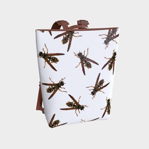 May include: White backpack with a repeating pattern of yellow and black wasps. The bag has brown straps and a brown handle. The design is printed on the front and sides of the bag.