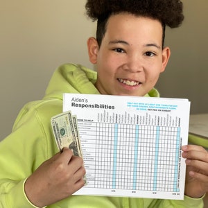 May include: A young person holding a chore chart and cash. The chart lists chores and has a grid for tracking daily completion. The text on the chart reads "Aiden's Responsibilities", "Help out with at least one thing per day", "Get good grades", "Keep room/bath clean", "Be good", "Get paid on Sunday!"