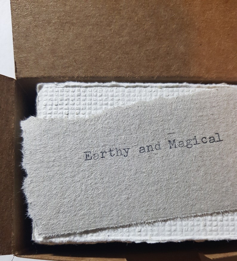 May include: A close-up of a white card with the text "Earthy and Magical" printed in black ink.