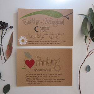 May include: Two brown cards with handwritten text on them. The top card says "Earthy and Magical" and "Handmade Recycled Paper." The bottom card says "Printing" and "I offer a printing service for my handmade papers!"