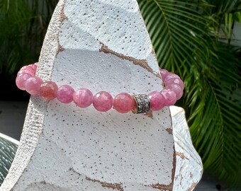 Faceted rubies surround a pavé diamond bead. Handmade and OOAK. Stretchy, fits most wrists 7”).
