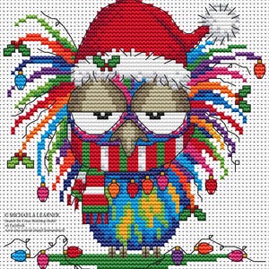 Pode incluir: Uma coruja de ponto cruz colorido usando um gorro de Papai Noel, óculos e um cachecol listrado. A coruja é decorada com luzes de Natal e tem um corpo semelhante a um globo. O texto é visível na parte inferior.