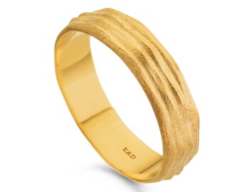 May include: A gold-colored ring with a textured, wood-like design on the outer band. The inner band is smooth and polished. The initials "E&D" are engraved on the inside of the ring. This ring is a piece of jewelry.