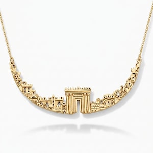 May include: A gold-toned necklace featuring a curved pendant shaped like a city skyline. The central element is a prominent archway with columns, flanked by various building silhouettes and a small, singular embedded clear gemstone.