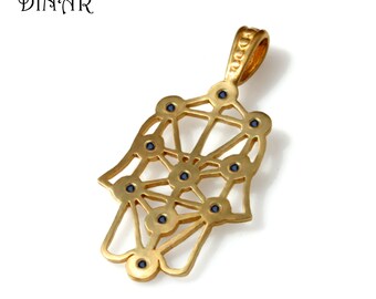 May include: Gold pendant necklace featuring a hamsa hand design with a tree of life pattern and blue gemstones. The pendant has the word "Dinar" engraved on the back.