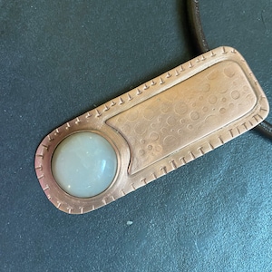 Cream moonstone set in long unisex copper pendant . leather cord choker.