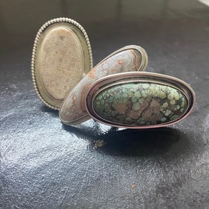 Pode incluir: Três anéis de prata com pedras de ágata de forma oval. As pedras são uma mistura de branco, marrom e verde.