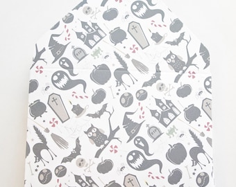 May include: A white and gray Halloween-themed gift box with a repeating pattern of ghosts, pumpkins, bats, witch hats, and haunted houses. The box is shaped like a house.