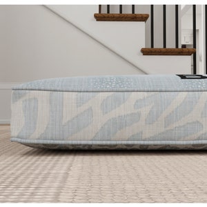 May include: A light blue cushion with a white and blue patterned design. The cushion has a black border and the word "BOHO" printed on it.