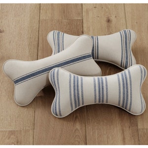 May include: Three bone-shaped pillows with a white and blue striped fabric design.