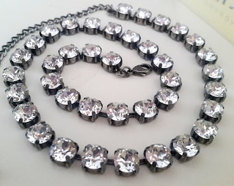 Puede incluir: Un collar de cadena de plata con una fila de piedras de cristal transparentes. El collar está hecho de metal y tiene un diseño simple.