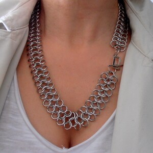 May include: A silver chain necklace with a clasp closure. The necklace is made of interlocking metal rings.