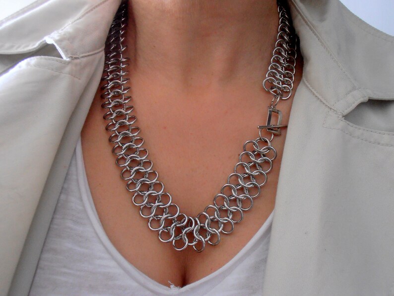May include: A silver chain necklace with a clasp closure. The necklace is made of interlocking metal rings.