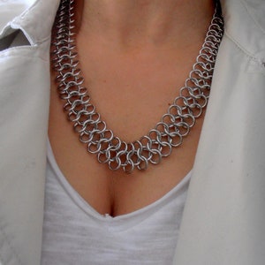 May include: A silver chainmail necklace with a double row of interlocking metal rings.