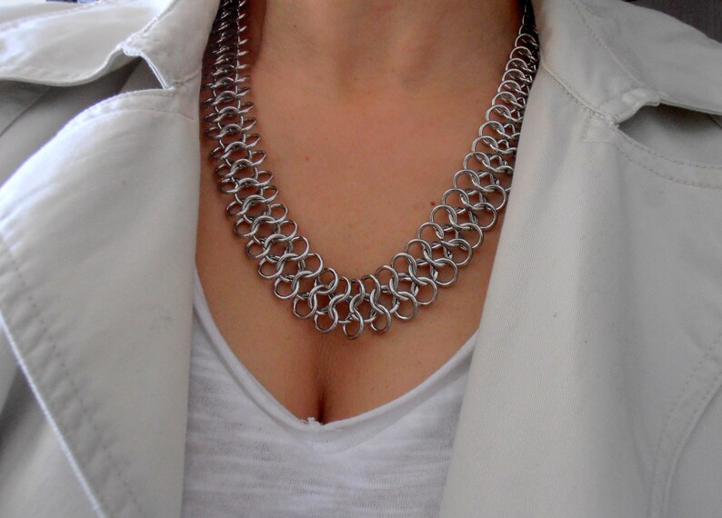 May include: A silver chainmail necklace with a double row of interlocking metal rings.