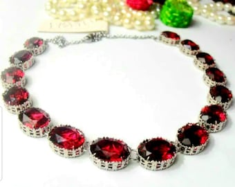 Peut inclure: Un collier en argent avec une chaîne et des pierres précieuses rouges de forme ovale. Les pierres précieuses sont serties d'argent et ont un design facetté.