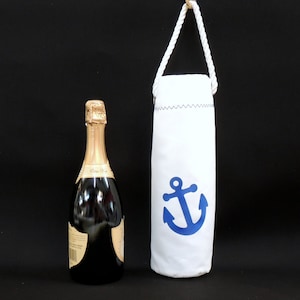 May include: White wine bottle bag with a blue anchor design. The bag has a white drawstring closure and is made of a canvas-like material.