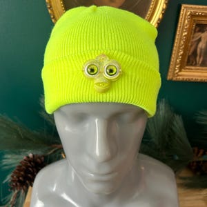 May include: A white ceramic mug with a black handle and the text "But First, Coffee" in a bold, black font. The mug is set against a blurred background, suggesting a cozy setting. The mug appears to be approximately 4 inches tall.