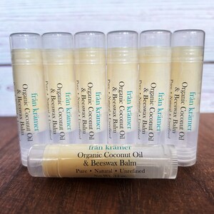 Pu&ograve; includere: Una collezione di tubetti di balsamo per le labbra con contenitori in plastica trasparente. Le etichette riportano "fr&aring;n kr&auml;mer Organic Coconut Oil & Beeswax Balm". I balsami per le labbra sono disposti su una superficie di legno. Ogni tubetto contiene 4.25 grammi di prodotto.