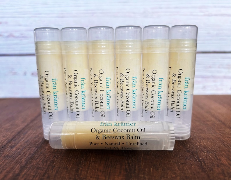 Pu&ograve; includere: Una collezione di tubetti di balsamo per le labbra con contenitori in plastica trasparente. Le etichette riportano "fr&aring;n kr&auml;mer Organic Coconut Oil & Beeswax Balm". I balsami per le labbra sono disposti su una superficie di legno. Ogni tubetto contiene 4.25 grammi di prodotto.
