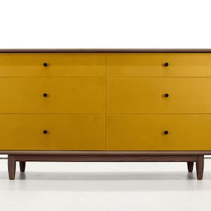 May include: A six-drawer dresser with a walnut wood frame and yellow painted drawers. The dresser has black knobs on each drawer.