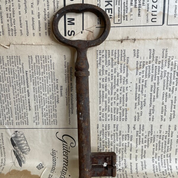 A large, rusty and old door key.