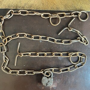 A rusted cow chain with a small padlock.